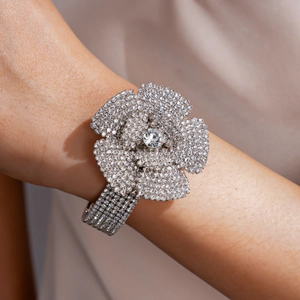 Detailaufnahme eines funkelnden fünfreihigen Strass-Blumenarmreifs an einem weiblichen Handgelenk