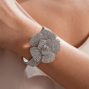 Detailansicht eines fünfreihigen Strass-Armreifs mit großem Blumendesign am Handgelenk.