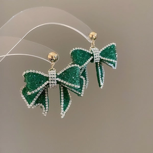 Detailaufnahme eleganter grüner Kristall-Schleifenohrringe mit glitzerndem Strass-Rand