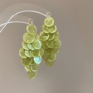 Détail rapproché de boucles d'oreilles pendantes en paillettes de verre vert clair
