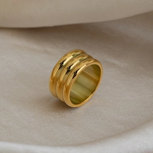 Detail of a 18K gold plated wide triple band ring with polished textured metal finish