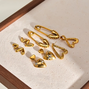 Vista macro di orecchini vintage a cuore e spilla da balia placcati in oro 18 carati
