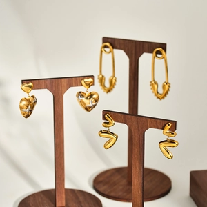 Orecchini vintage a cuore e spilla da balia esposti su supporti in legno per gioielli