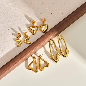Collezione di orecchini vintage in oro 18K con design a cuore e spilla da balia.