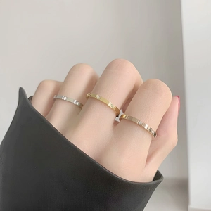 Close-up of minimalist gold, silver, and rose gold rings with cubic zirconia on female hand