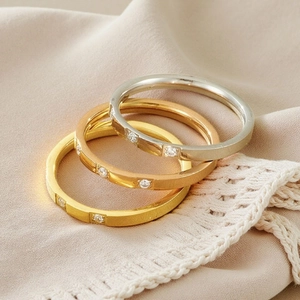 Close-up of three minimalist rings in gold, silver, and rose gold with zircon stones