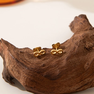 18K gold plated stainless steel infinity stud earrings on dark wood background
