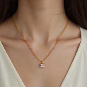 Nahaufnahme eines quadratischen Zirkonia-Anhängers an einer 18k vergoldeten Doppelkette.