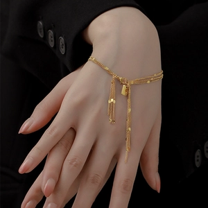 Detail of 18K gold-plated multi-layer tassel bracelet with delicate gold beads and charms