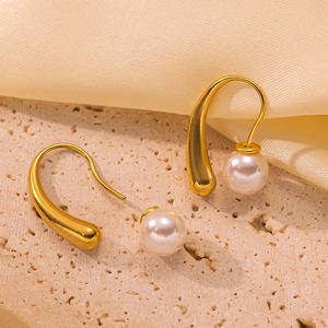 Elegant French-style gold teardrop earrings with high-luster pearls on textured stone