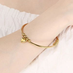 Elegant gold stainless steel bangle bracelet featuring beads and heart pendant charm