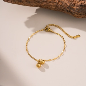 Gold-plated stainless steel bead necklace with lobster clasp on natural wood background
