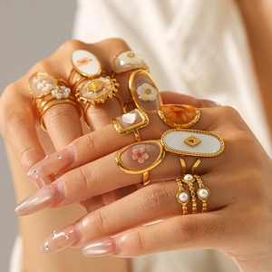 Detailed view of gold-plated stainless steel rings with preserved flower and shell inlays.