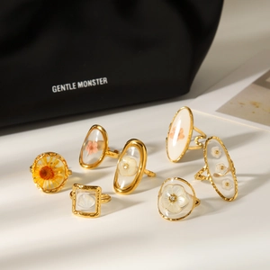 A detailed collection of gold-plated stainless steel rings with embedded dried flowers