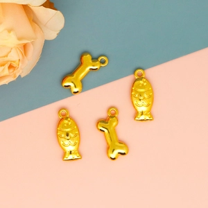Detailopname van schattige goudkleurige vis- en botvormige hangers voor DIY-sieraden.