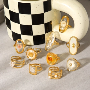 Vintage gold rings collection with eternal flowers and pearls by a checkered mug.