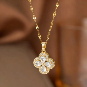 Macro detail of gold four-leaf clover necklace with sparkling pear-cut purple cubic zirconia