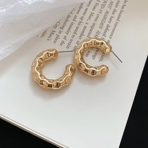 Elegant gold-toned C-shaped hoop earrings with hammered texture and silver pins for women.
