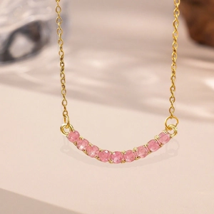 Elegant gold necklace featuring a curved pendant set with eleven sparkling pink gemstones