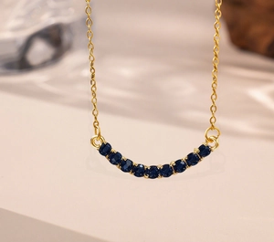 Close-up of golden necklace with eleven round blue gemstones in a smile curved setting