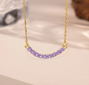 Detail of gold smile necklace featuring eleven purple round-cut gemstones on fine O-chain