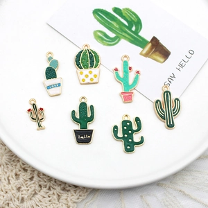 Variety of colorful cactus enamel charms for DIY jewelry making on white plate