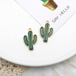 Detailed macro view of green enamel cactus alloy charms on a white ceramic plate decor