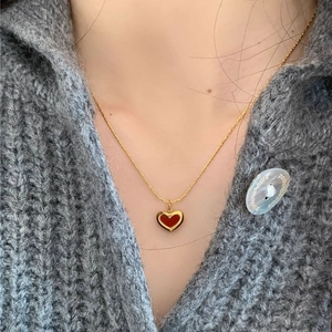 Collier à pendentif coeur rouge minimaliste en acier doré 18K sur un modèle en pull gris