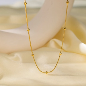 Collier à perles dorées minimaliste avec chaîne serpent sur fond de soie élégant