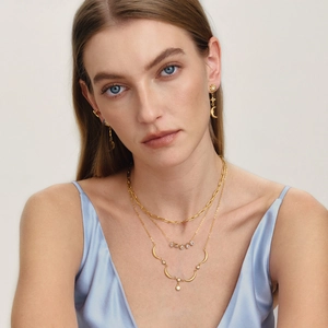 Close-up of elegant 18K gold layered necklaces with teardrop zircons on female model