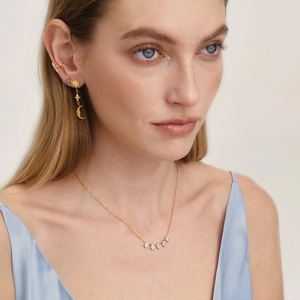 Model showcases 18K gold teardrop cubic zirconia necklace with sun and moon earrings.