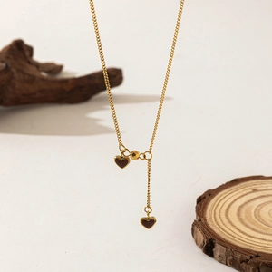 Elegante collana in acciaio al titanio dorato con due raffinati ciondoli a cuore rosso
