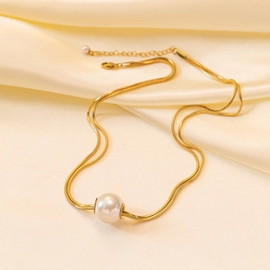 Collier double rang en maille serpent dorée avec perle sur un tissu en soie champagne