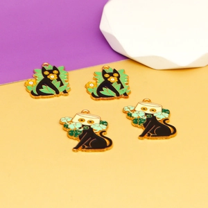Detailed macro view of four black cat enamel charms with leaf and flower motifs.