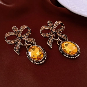 Macro view of vintage palace style earrings featuring amber gemstones and bowknot motifs