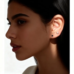 Detailed view of s925 silver star and black diamond stud earrings on a model's ear