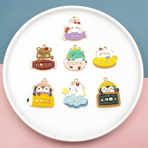 Close-up of seven cartoon animal enamel charms with Chinese blessings on a white plate.