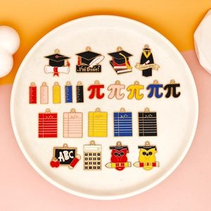 Sortierte Emaille-Anhänger zum Thema Abschluss mit Schul-Symbolen für DIY-Schmuck