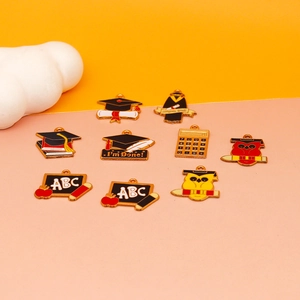 Verschiedene Abschluss-Emaille-Anhänger wie Hüte und Diplome für DIY-Schmuckherstellung.