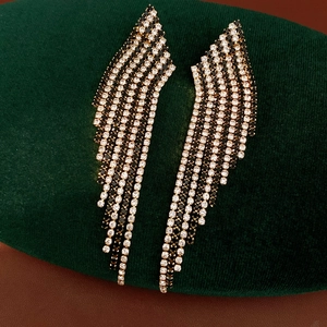 Detailed close-up showing black and white striped rhinestone tassel earrings on green velvet