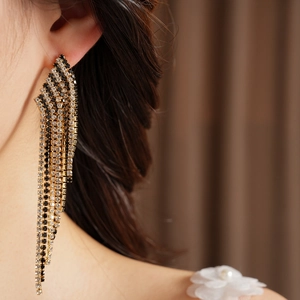 Close-up detail of vintage tassel earrings with black and clear rhinestones on ear.