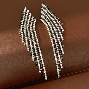 Detail view of shimmering black and white rhinestone tassel earrings on brown leather