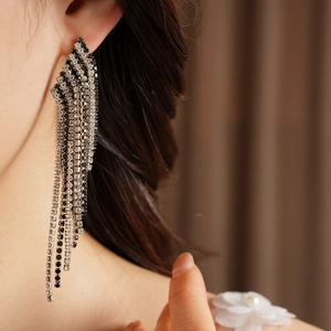 Close-up of vintage rhinestone tassel earrings with black and clear stones on ear.
