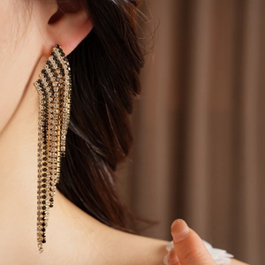 Close-up of vintage tassel earrings with black and white rhinestones on an elegant model.