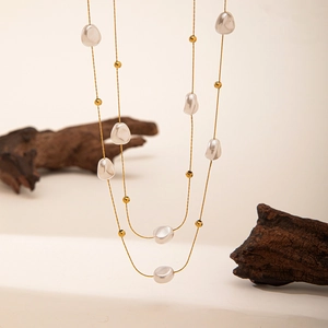 Elegant baroque pearl layered necklace with golden beads on a minimalist white background