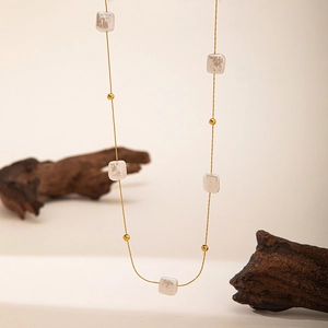 Elegant gold chain necklace featuring white square baroque pearls in a minimalist style
