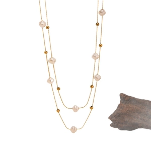 Elegant double-layered baroque pearl necklace with gold beads on a minimalist background