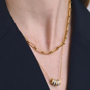 Gros plan d'un collier multicouche en acier inoxydable doré 18 carats avec bagues cristal