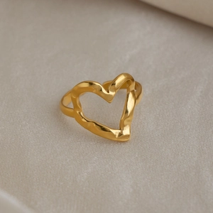 Dettaglio macro dell'anello a cuore in oro martellato con texture lucida e onde eleganti