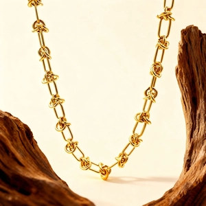 Modern vintage gold metal necklace featuring polished oval links and knotted design accents